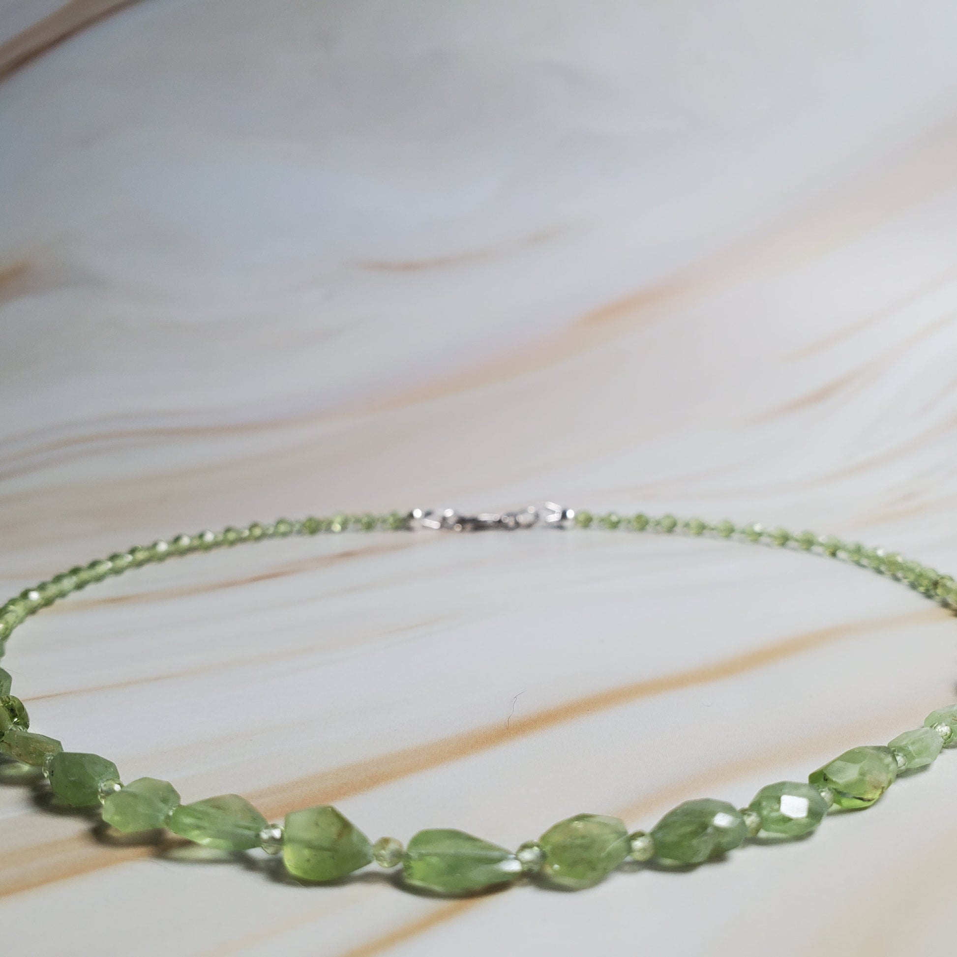 Green beaded necklace on a marble surface