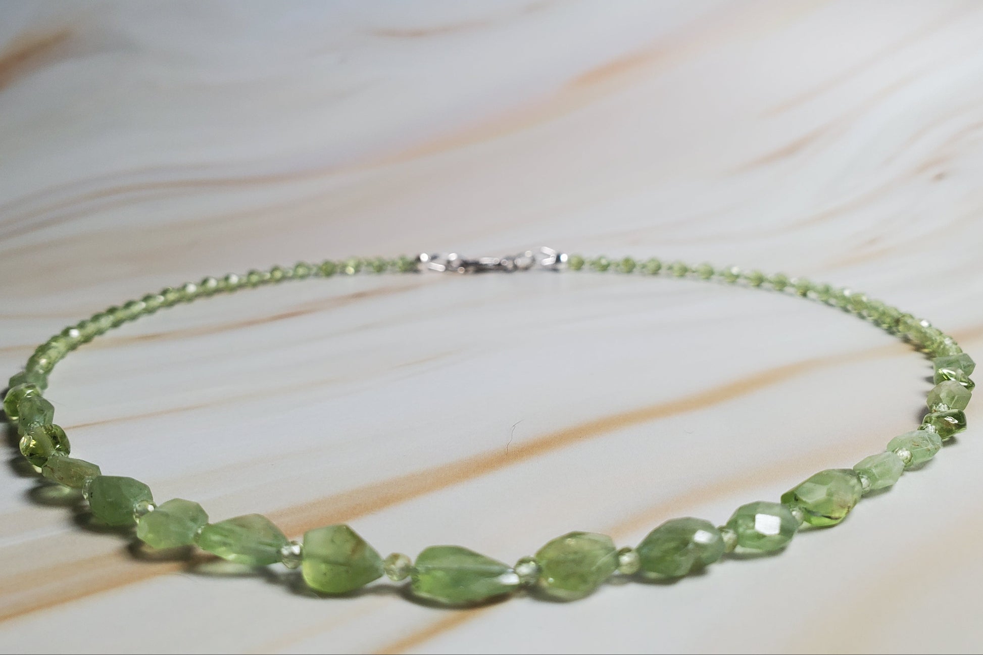 Green beaded necklace on a light wooden surface