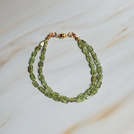 Green beaded bracelet on a soft white fabric background