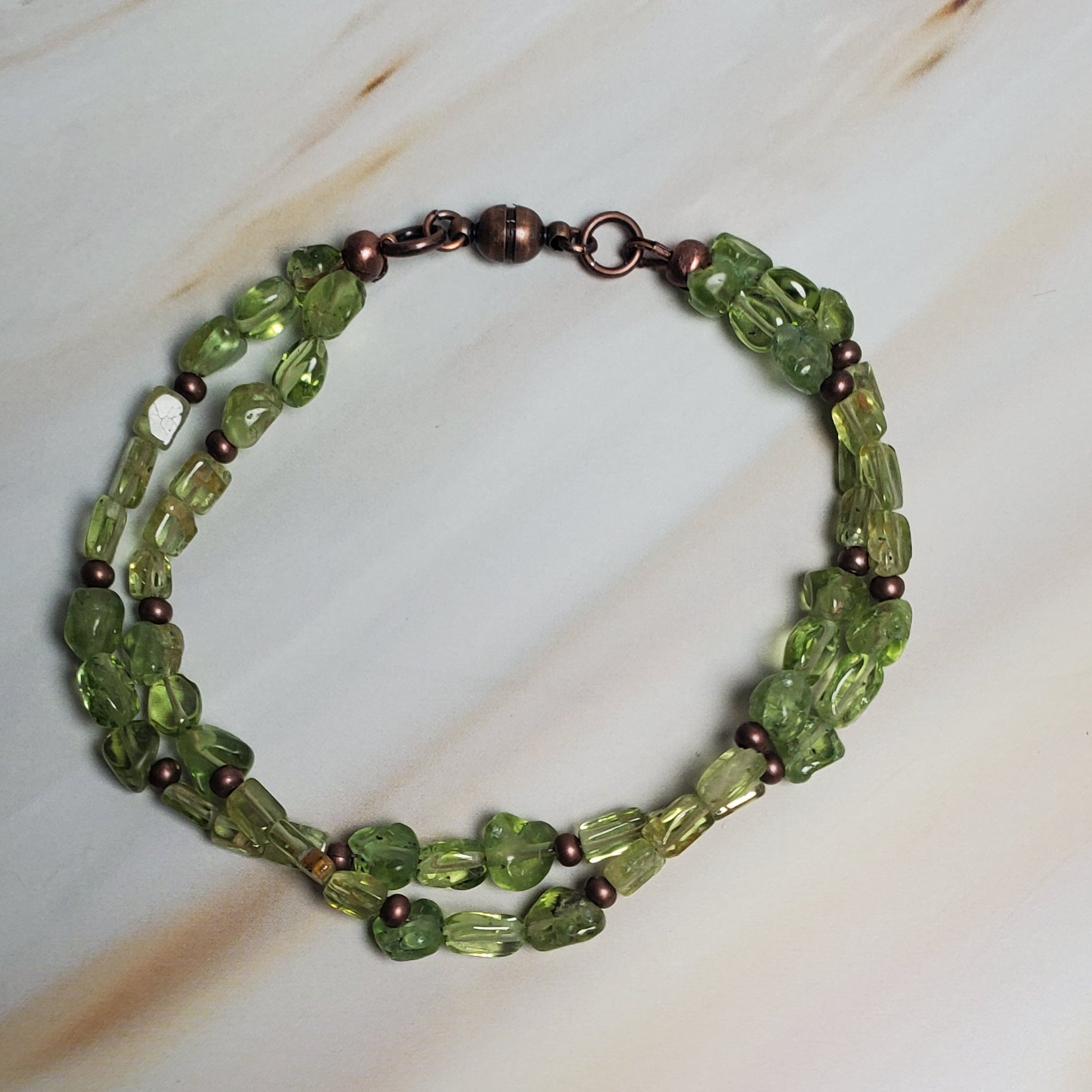 Green beaded bracelet on a textured beige surface