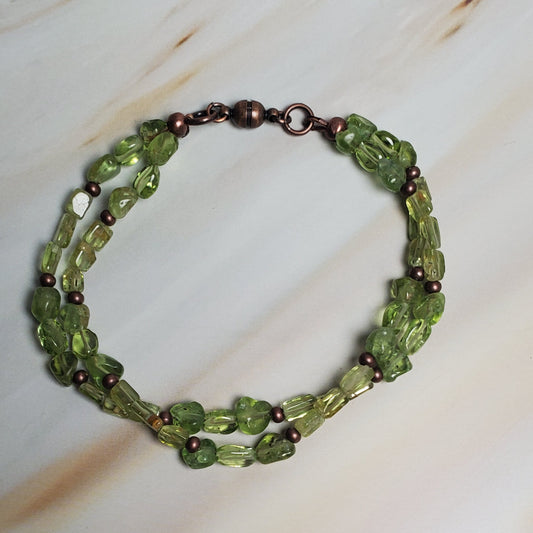 Green beaded bracelet on a textured beige surface