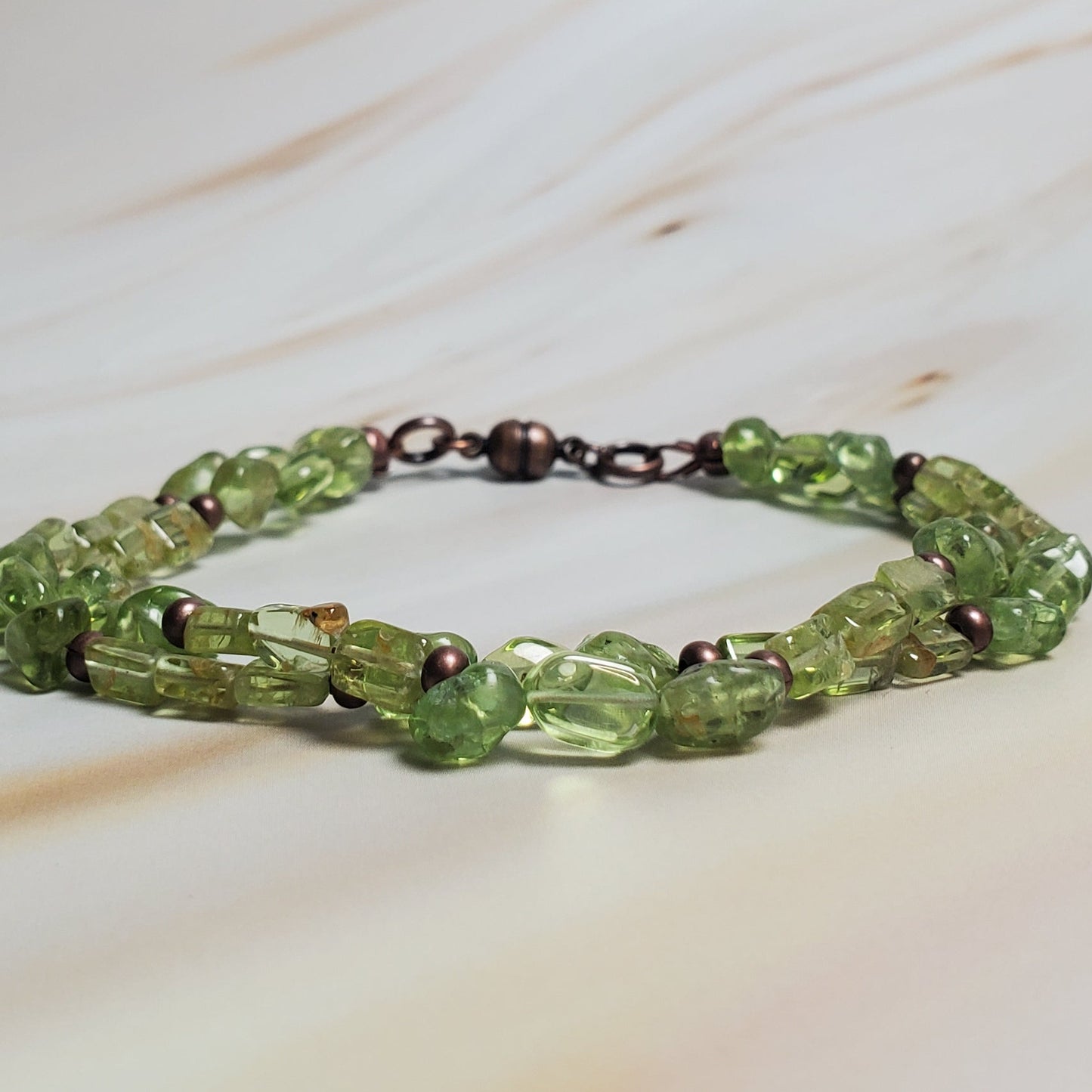 Green beaded bracelet on a marble surface