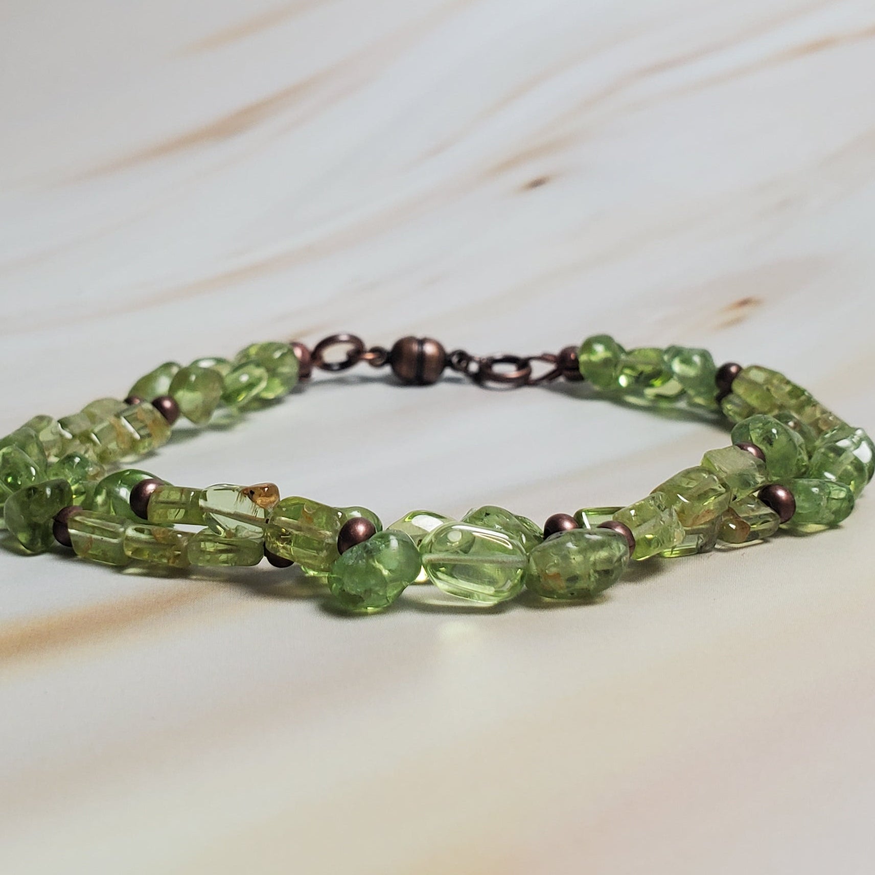 Green beaded bracelet on a marble surface