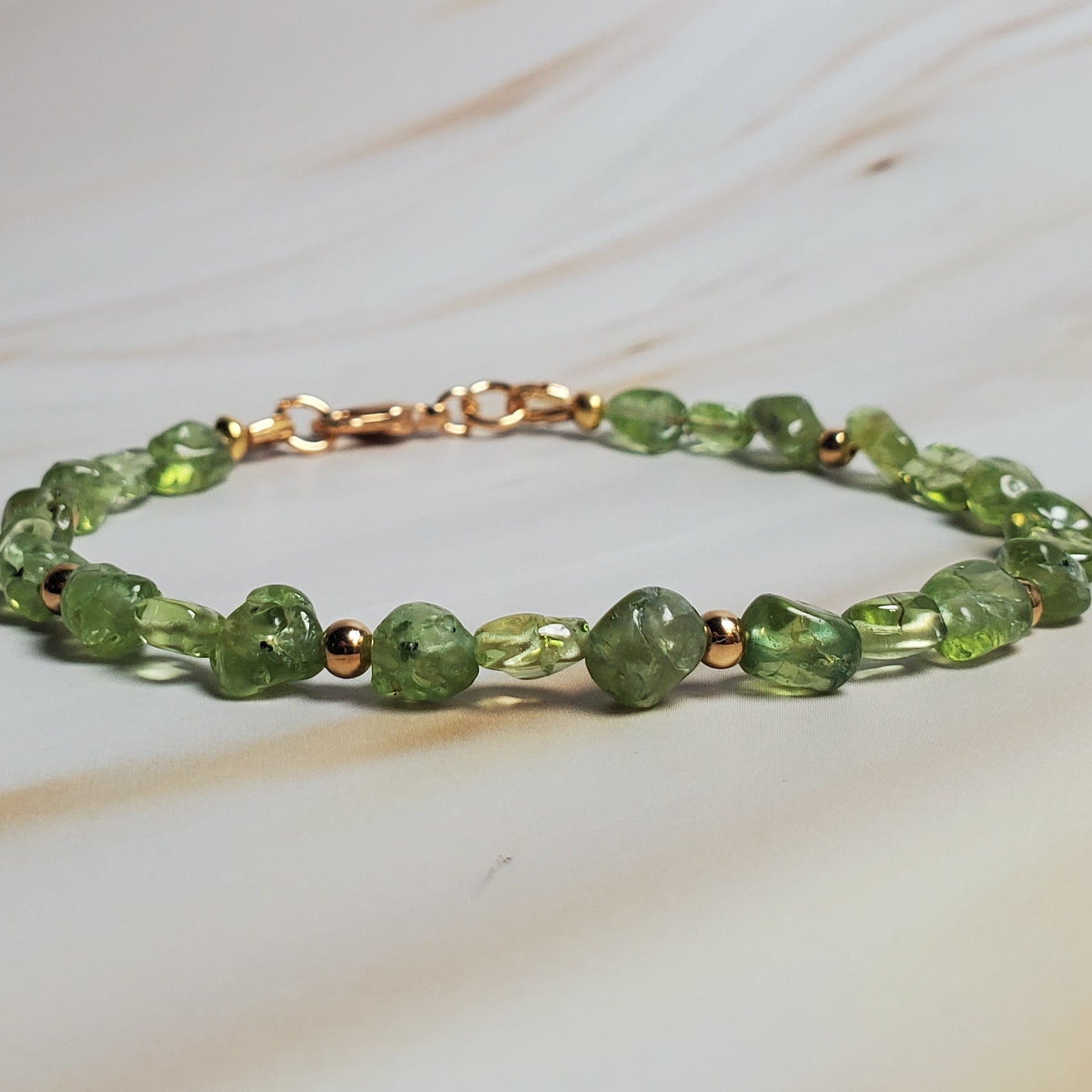 Green beaded bracelet on a marble surface