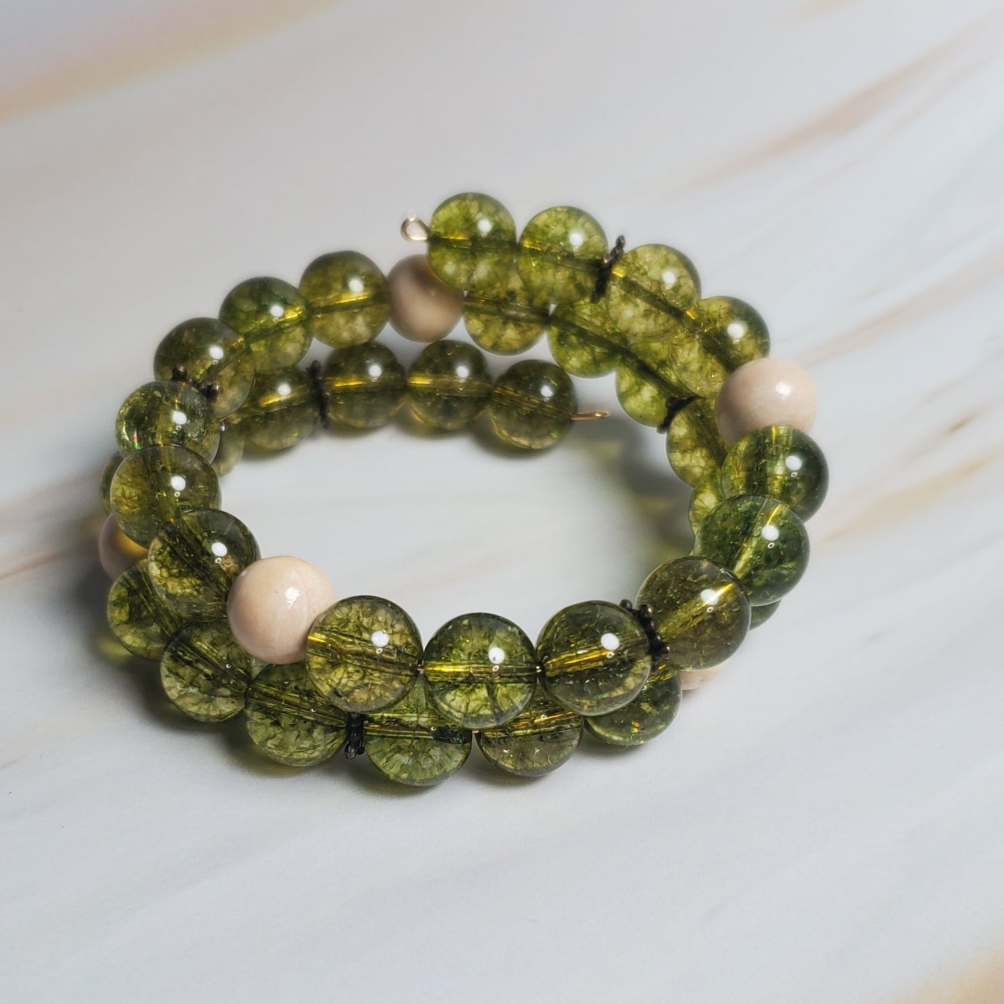 Green beaded bracelet on a white marble surface