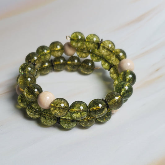 Green beaded bracelet on a white marble surface