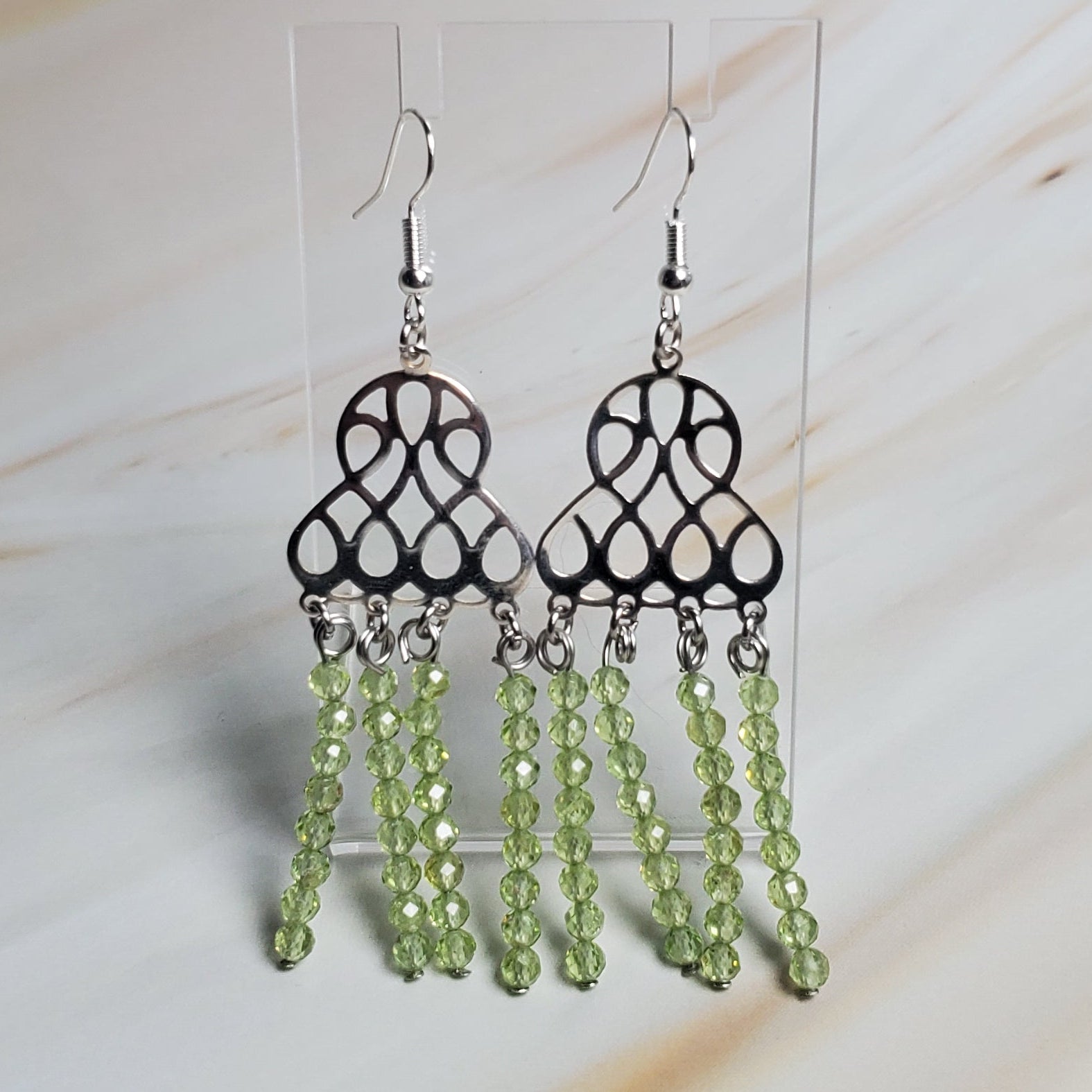 Earrings with green beads on a light marble background