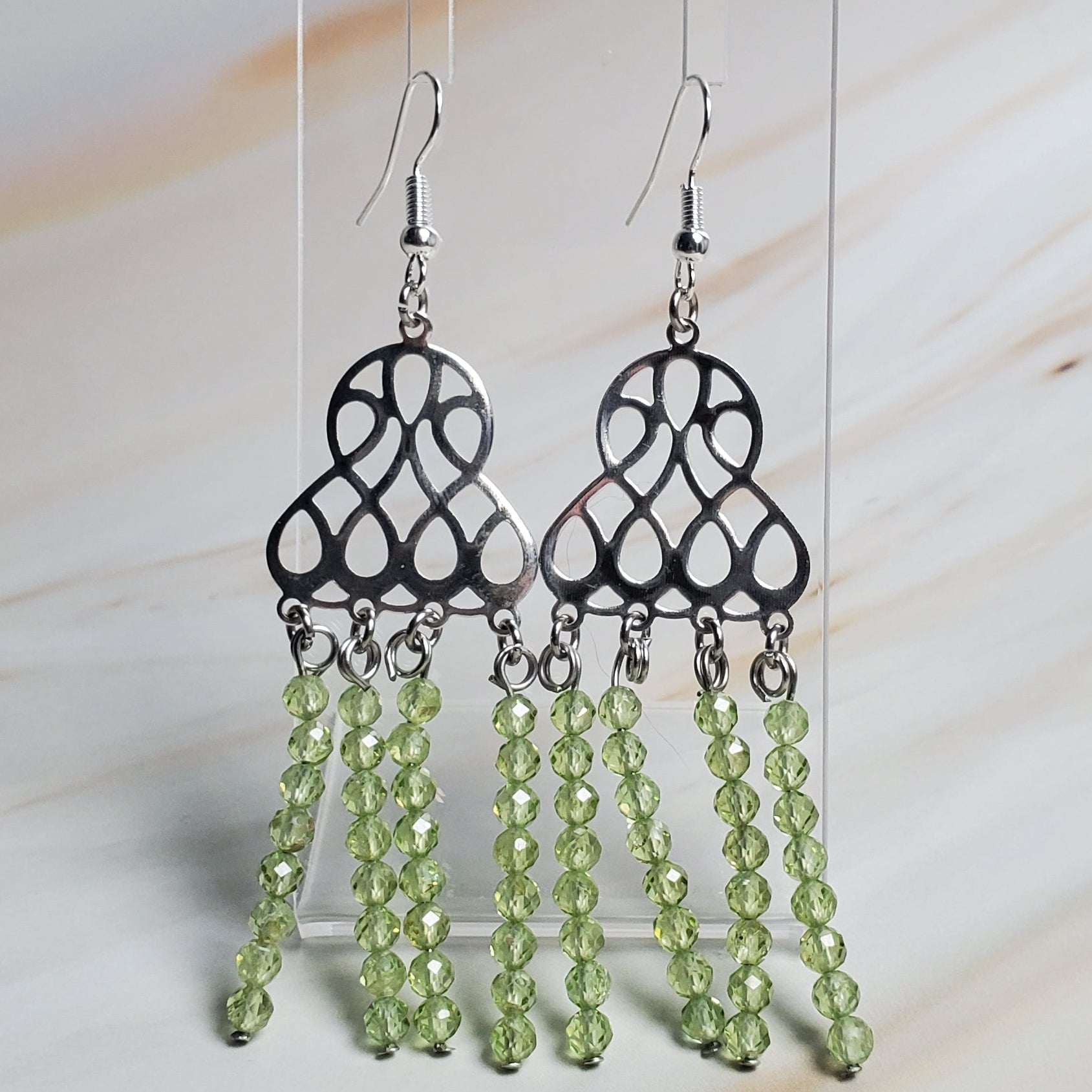 Pair of earrings with green beads on a light background