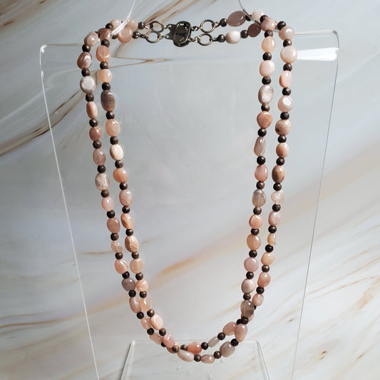 Necklace on a clear stand against a marble background