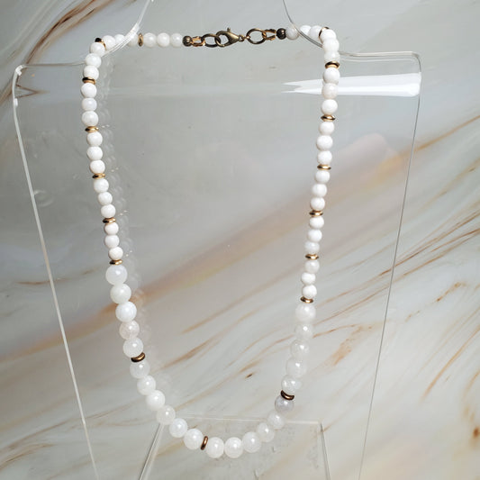 Moonstone necklace on a clear stand against a marble background