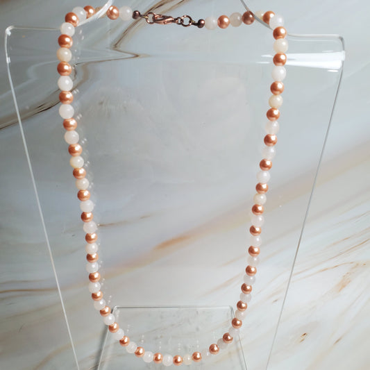Pearl necklace on a clear stand against a marble background