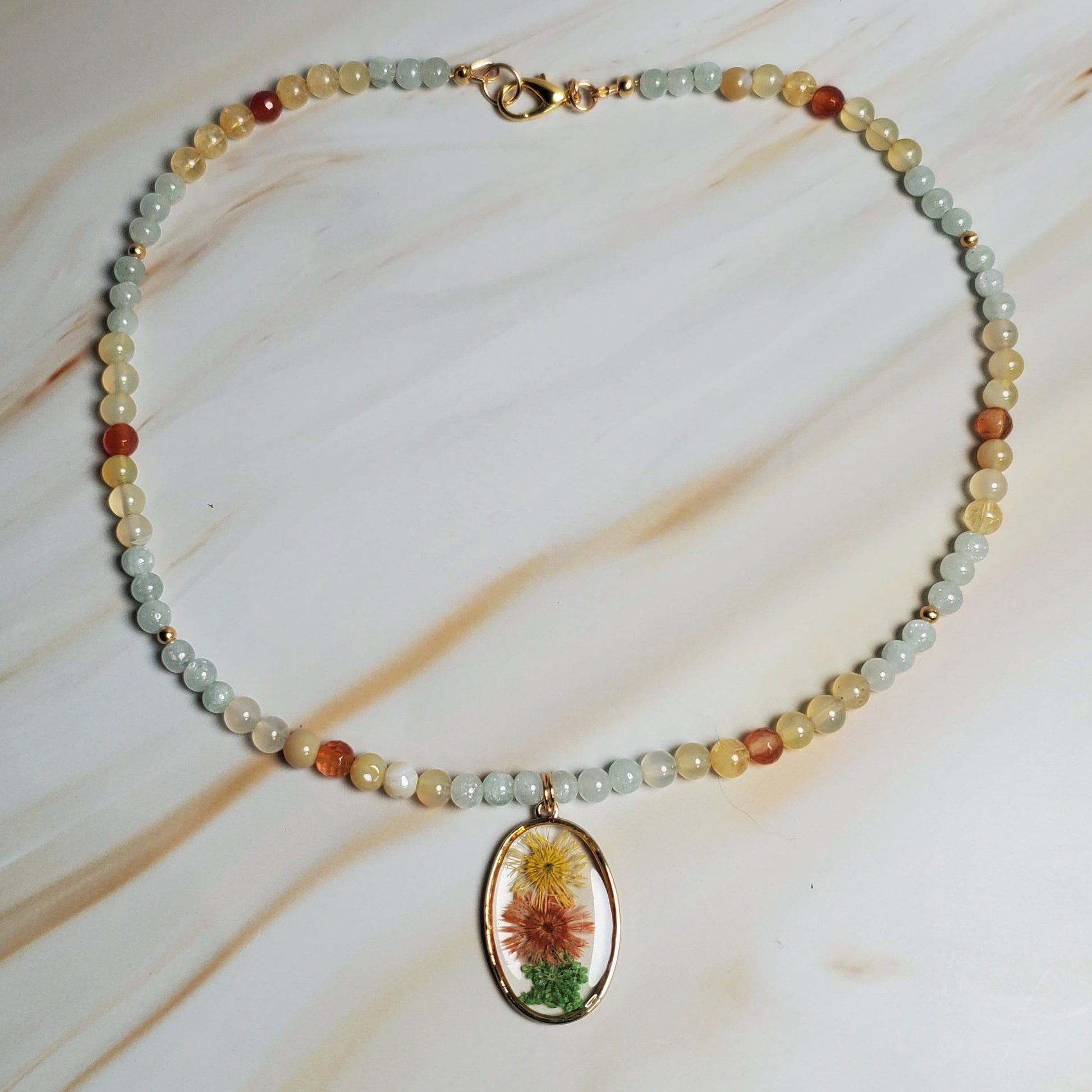 Beaded necklace with a colorful pendant on a marble surface
