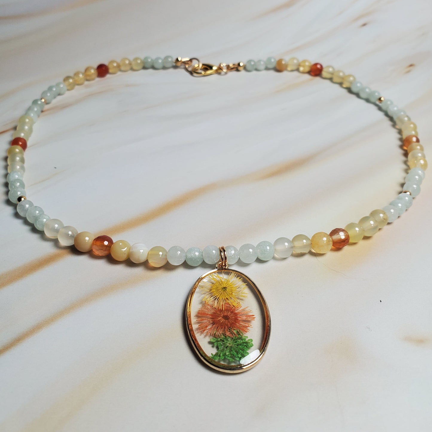 Beaded necklace with a floral pendant on a white fabric background