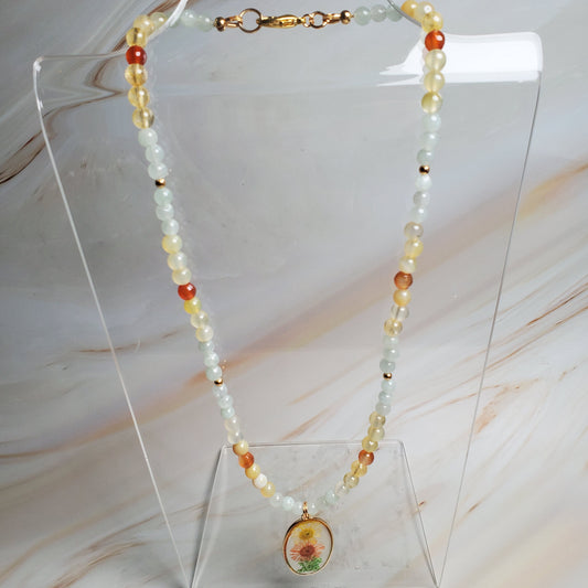 Beaded necklace on a clear stand against a marble background