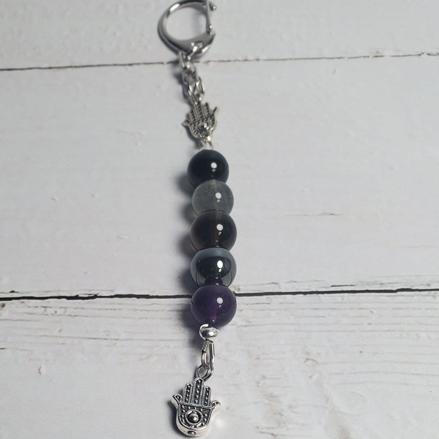 Beaded keychain with purple and black beads on a white wooden surface