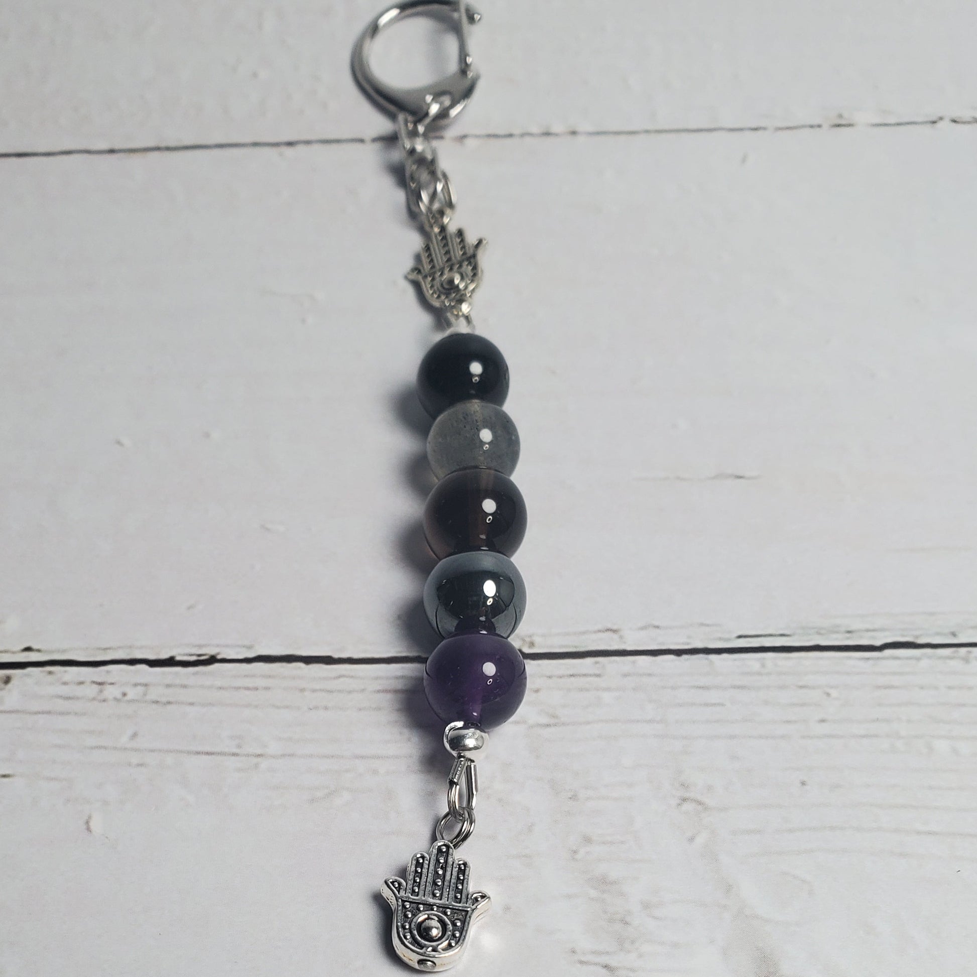 Beaded keychain with purple and black beads on a white wooden surface