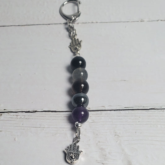 Beaded keychain with purple and black beads on a white wooden surface