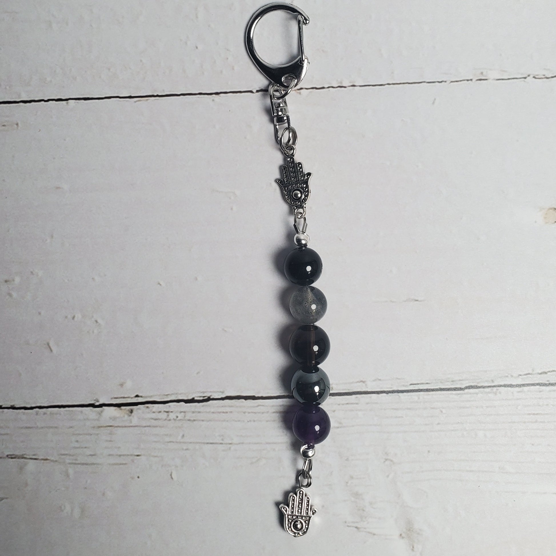 Intention Clip with black beads and silver clasp on a white wooden surface