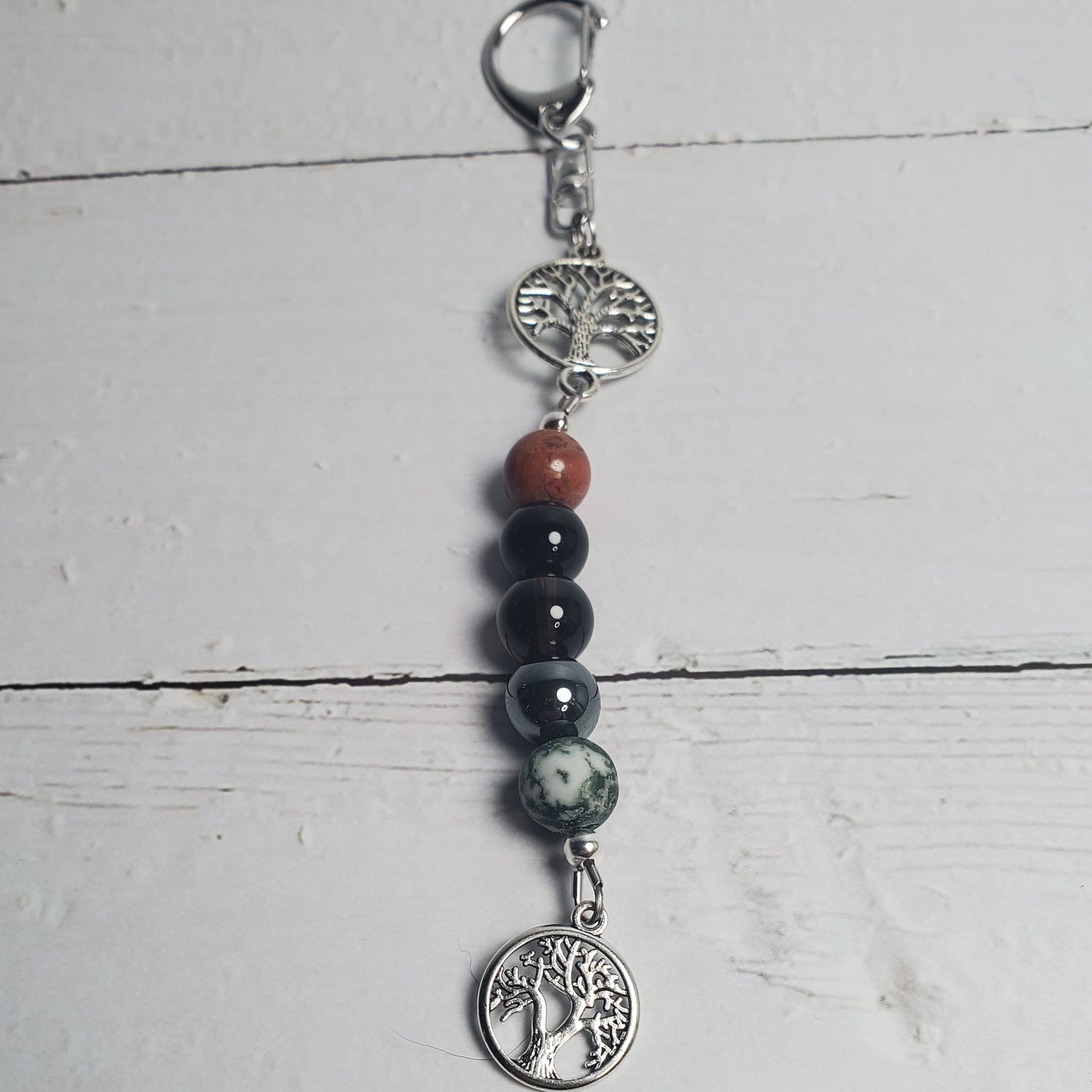 Intention Clip with beads and silver charms on a white wooden surface