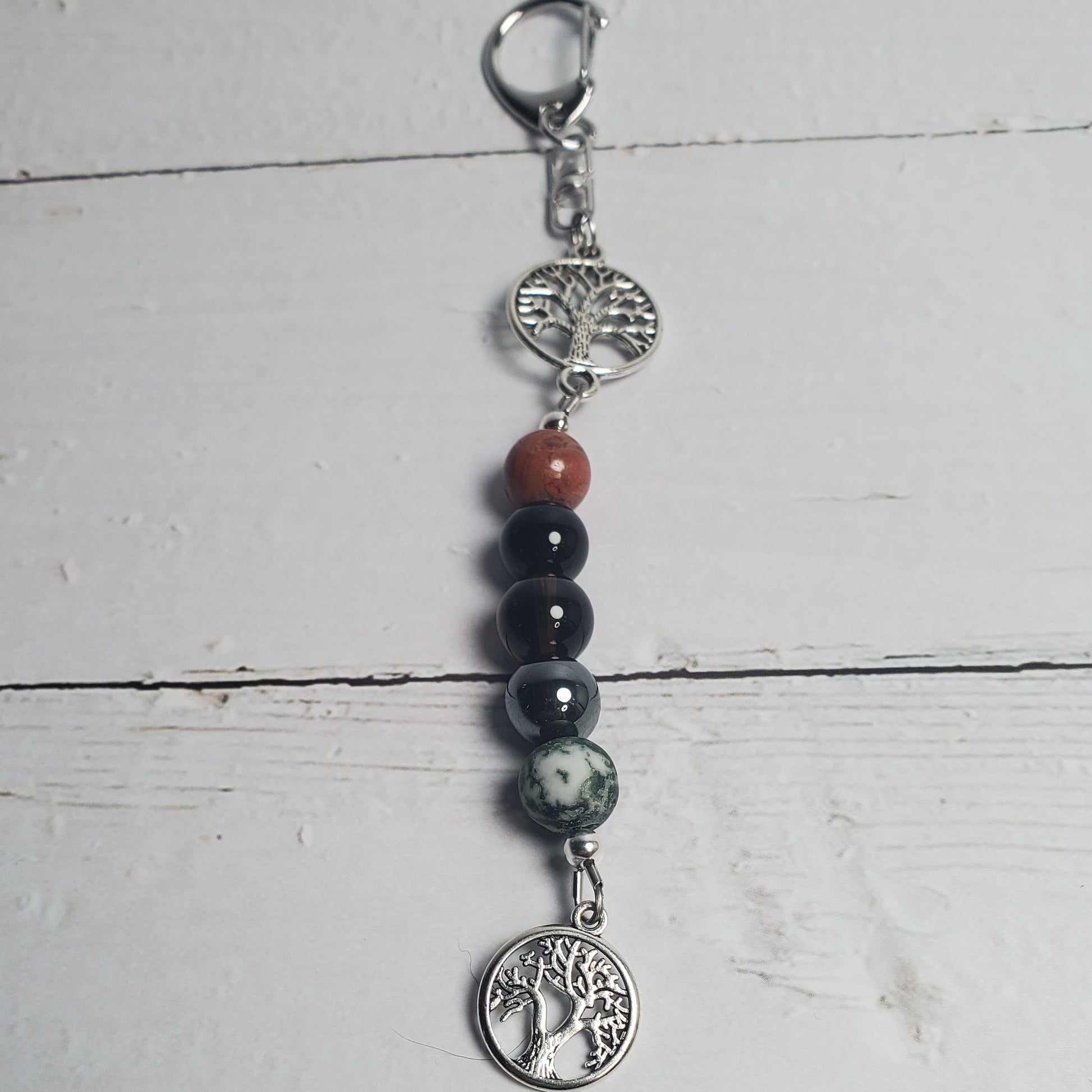 Intention Clip with beads and silver charms on a white wooden surface