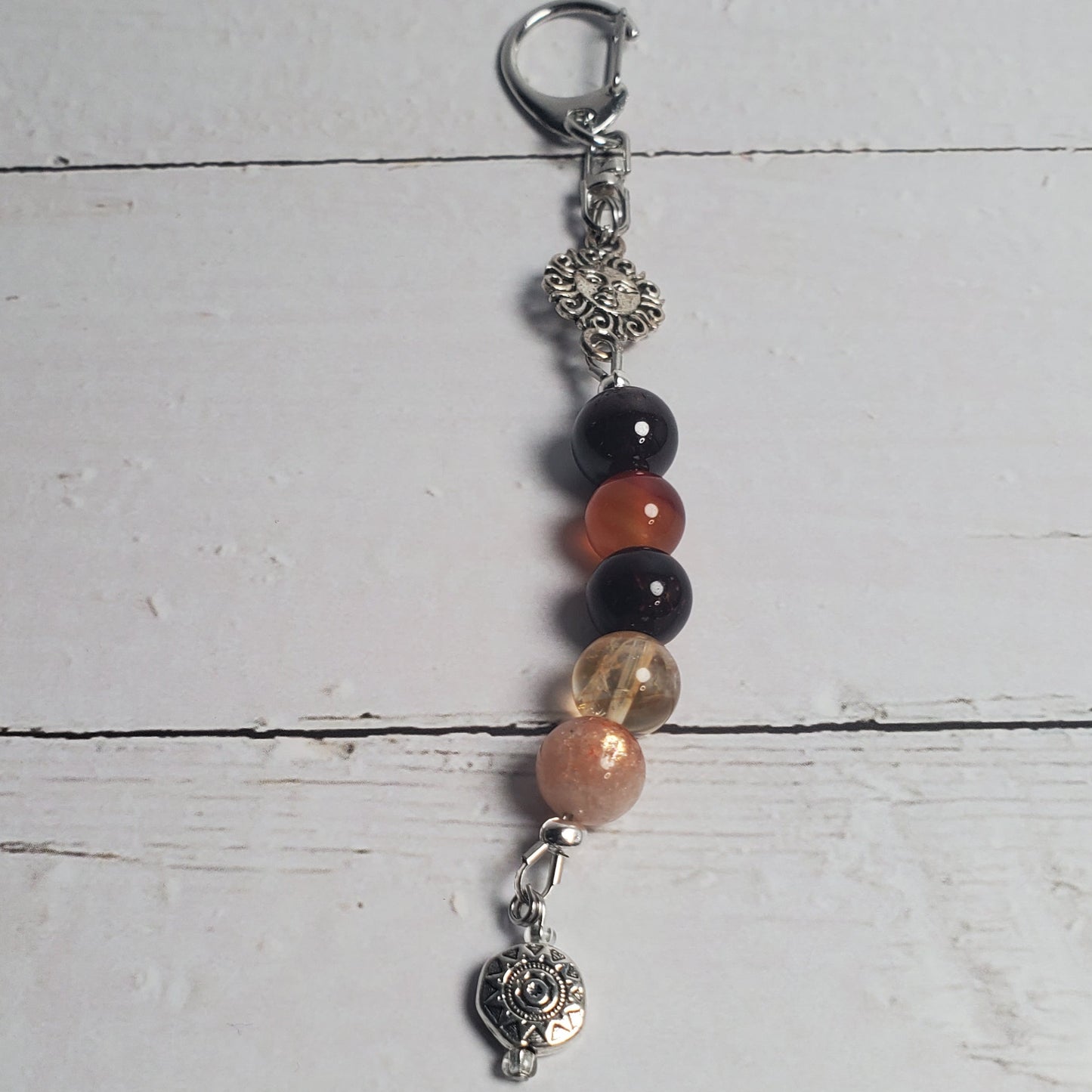 Beaded Intention Clip with black, red, and gold beads on a light wooden surface