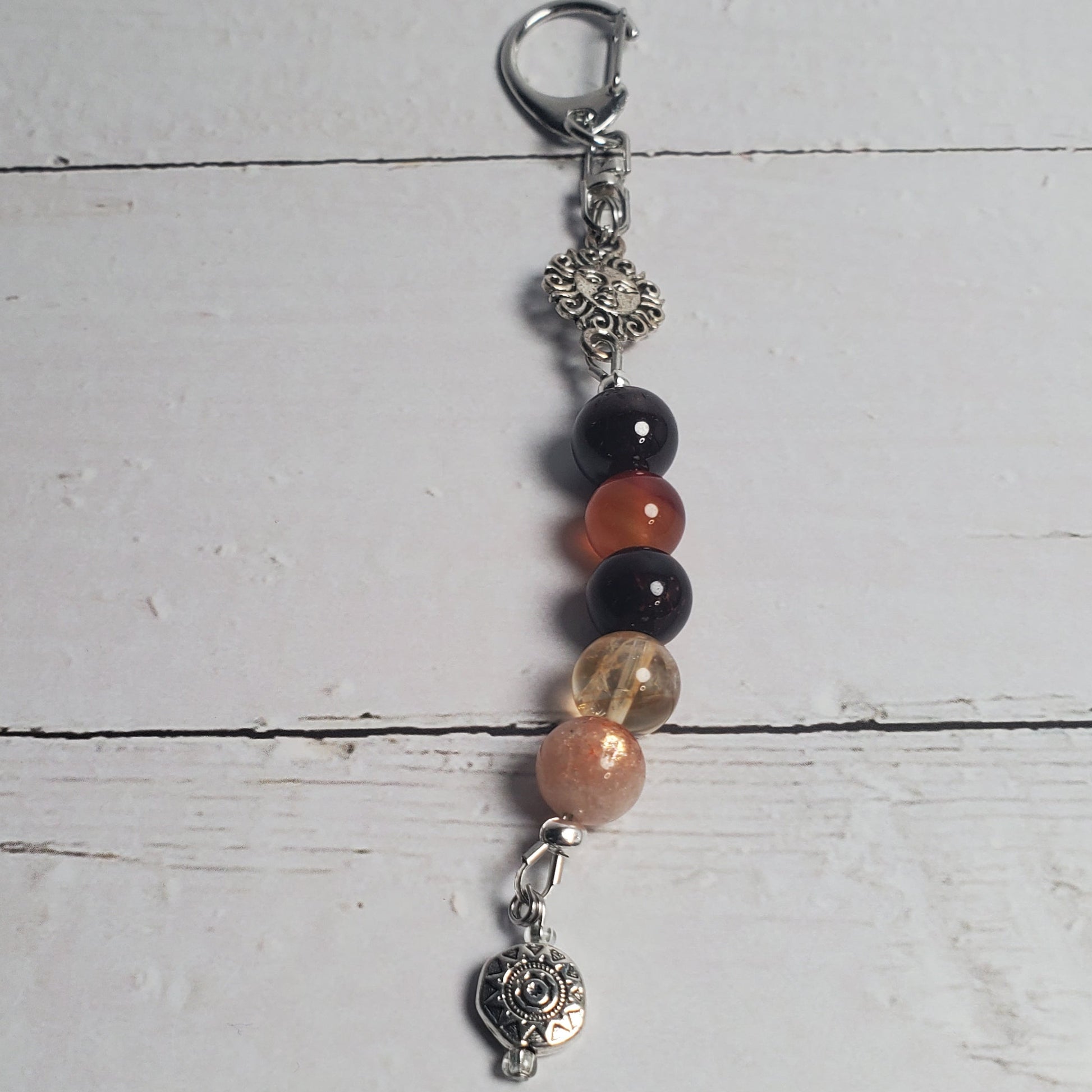 Beaded Intention Clip with black, red, and gold beads on a light wooden surface