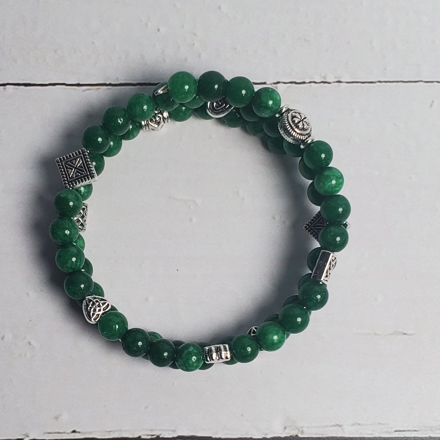 Green beaded bracelet on a white wooden surface