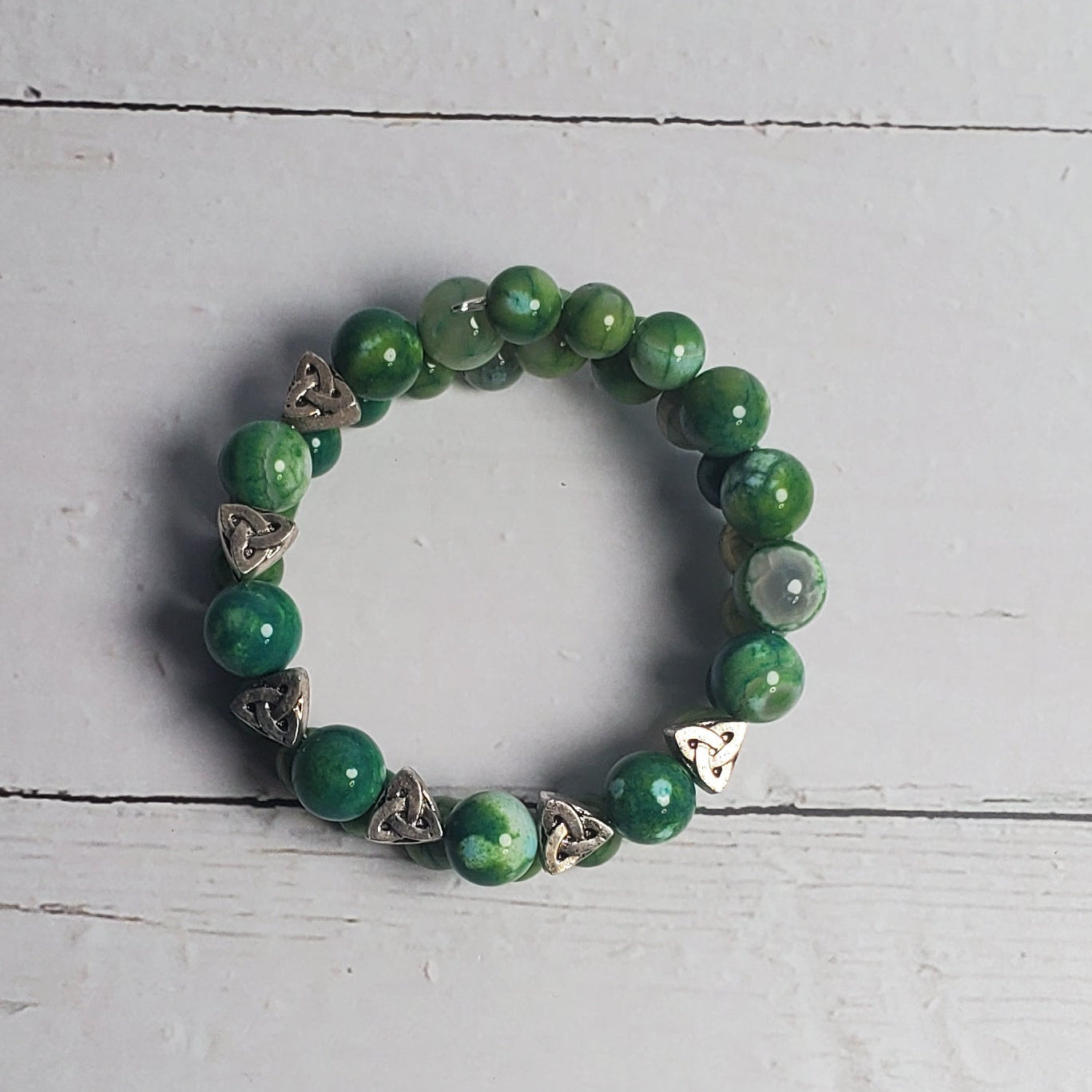Green beaded bracelet on a white wooden surface