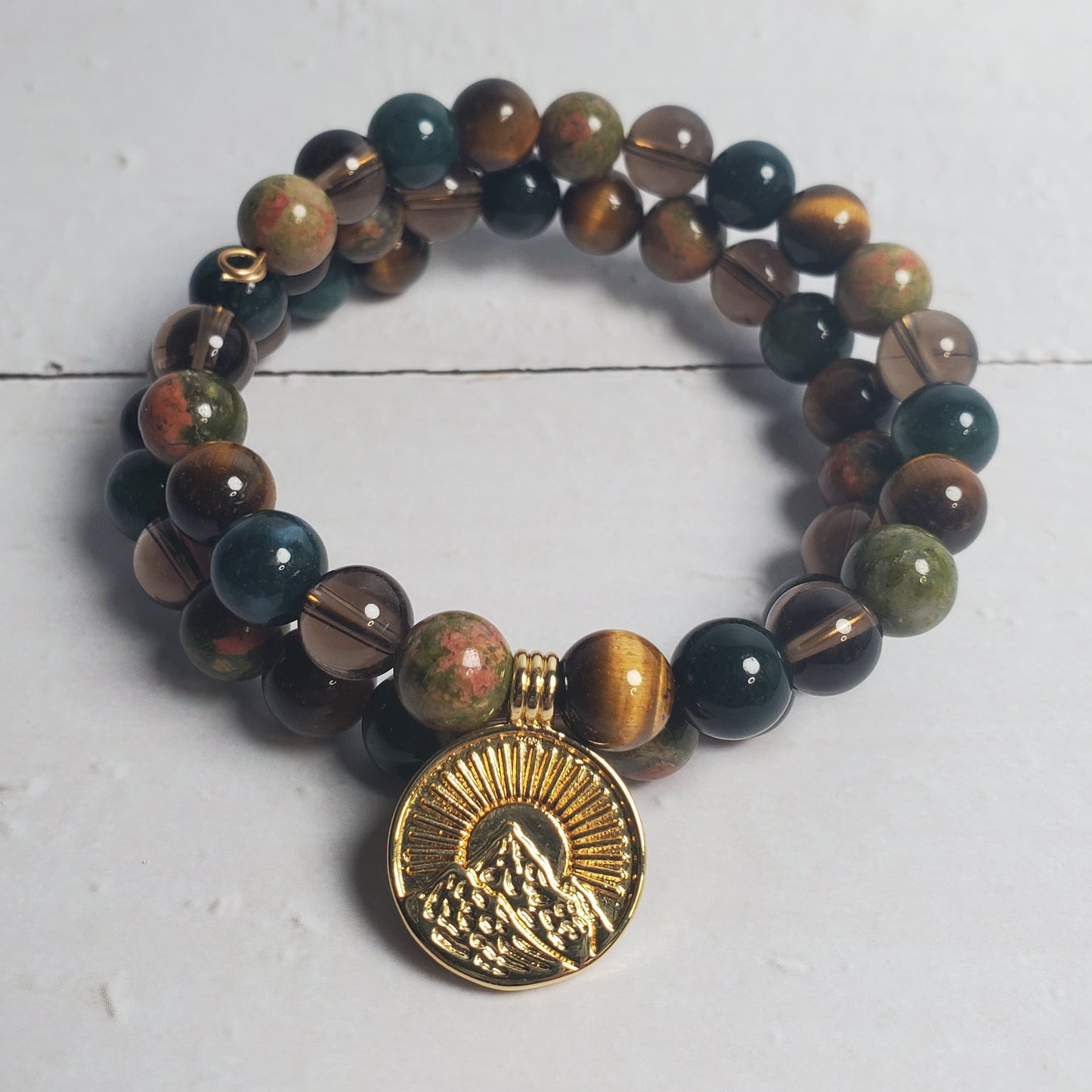 Beaded bracelet with a gold charm on a white wooden surface