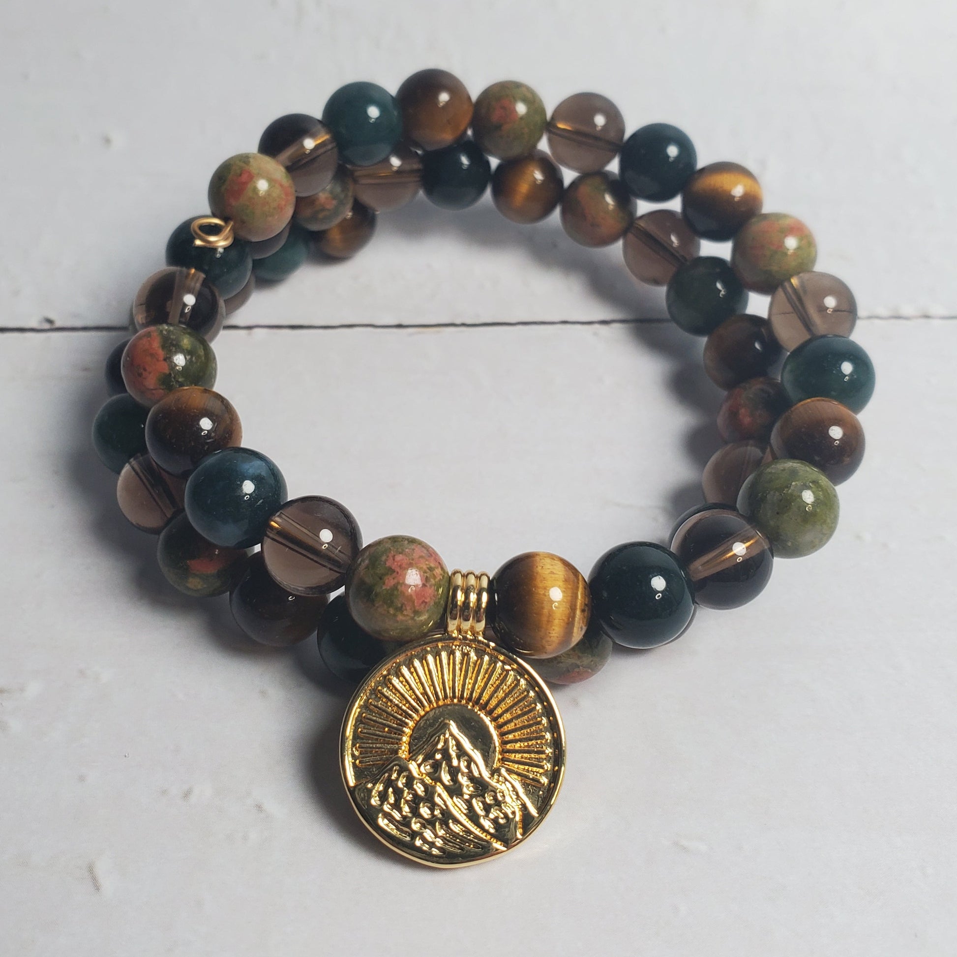 Beaded bracelet with a gold charm on a white wooden surface