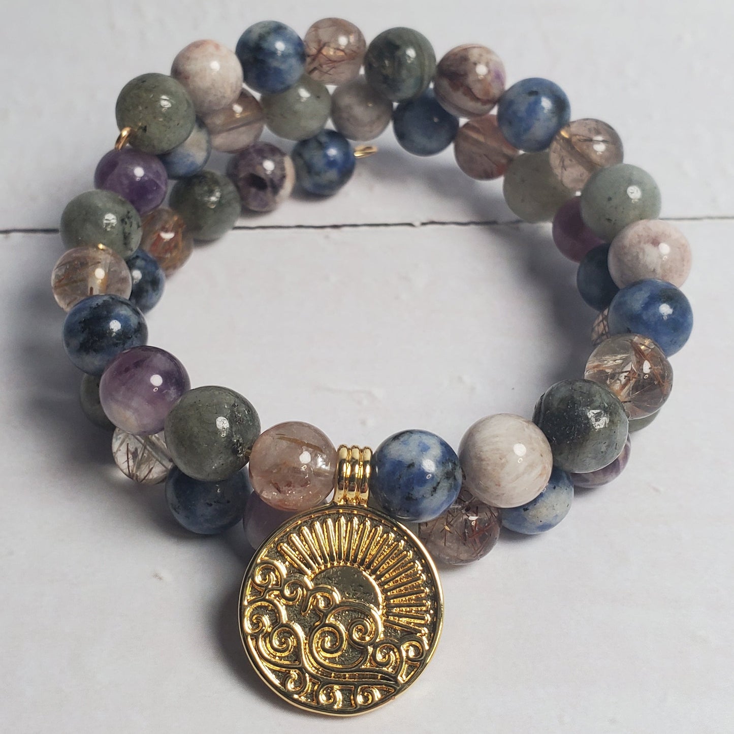 Multicolored beaded bracelet with a gold charm on a white wooden surface
