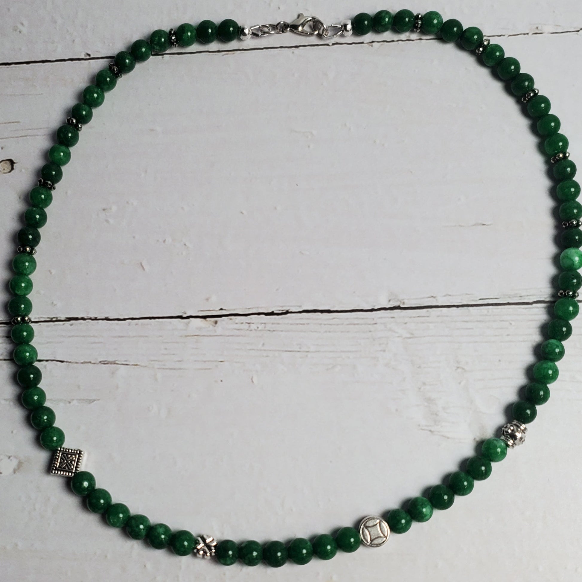 Green beaded necklace on a white wooden surface