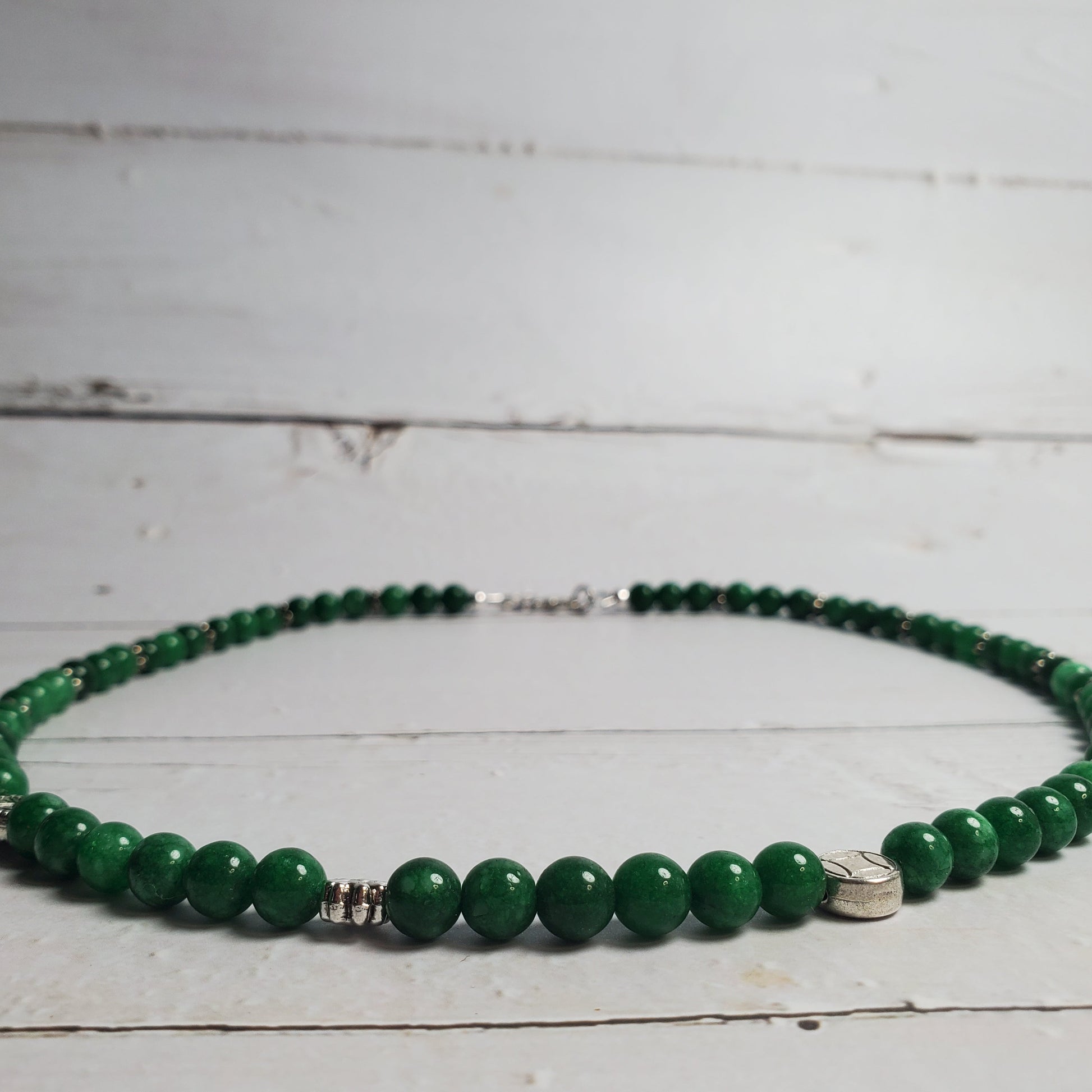 Green beaded necklace on a light wooden surface