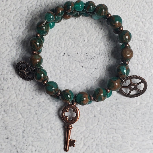 Handcrafted industrial bracelet featuring green resin quartz and copper steampunk gear charms on an adjustable memory wire cuff