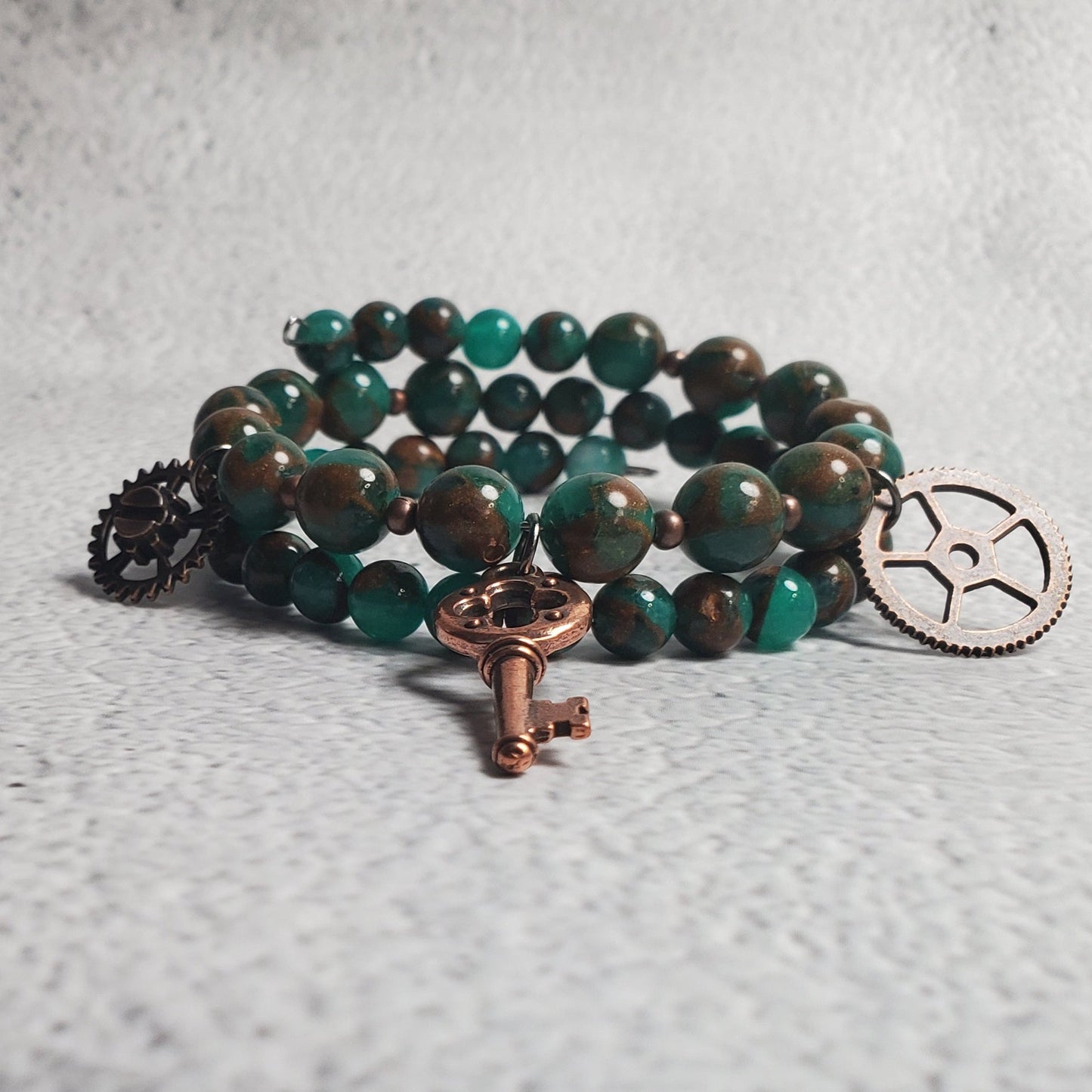 Handcrafted industrial bracelet with green resin quartz and copper steampunk charms on memory wire cuff
