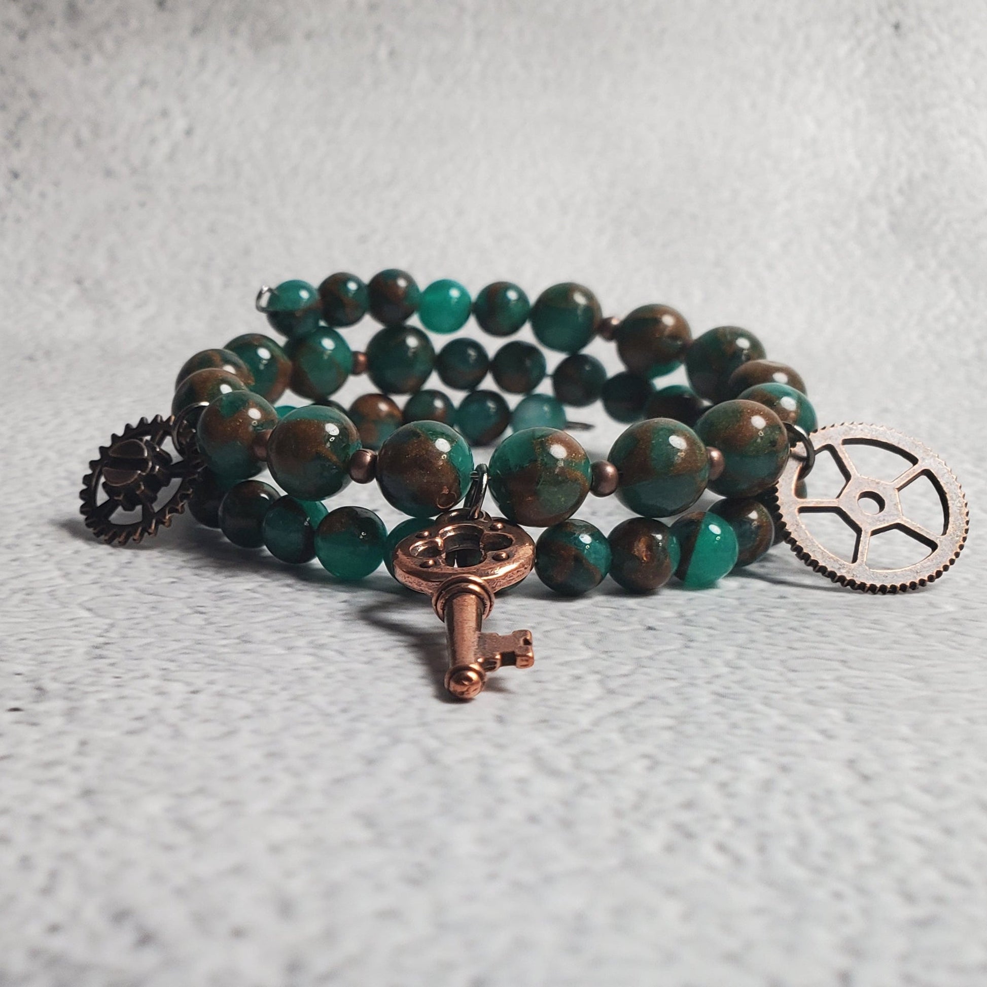 Handcrafted industrial bracelet with green resin quartz and copper steampunk charms on memory wire cuff