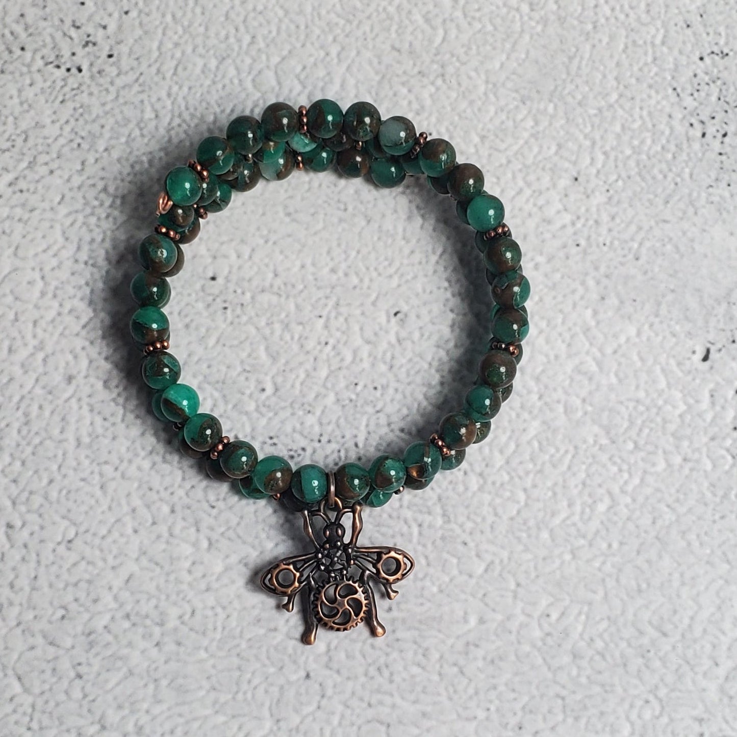 Handcrafted steampunk industrial bracelet with copper beetle charm and green resin sponge quartz on memory wire cuff