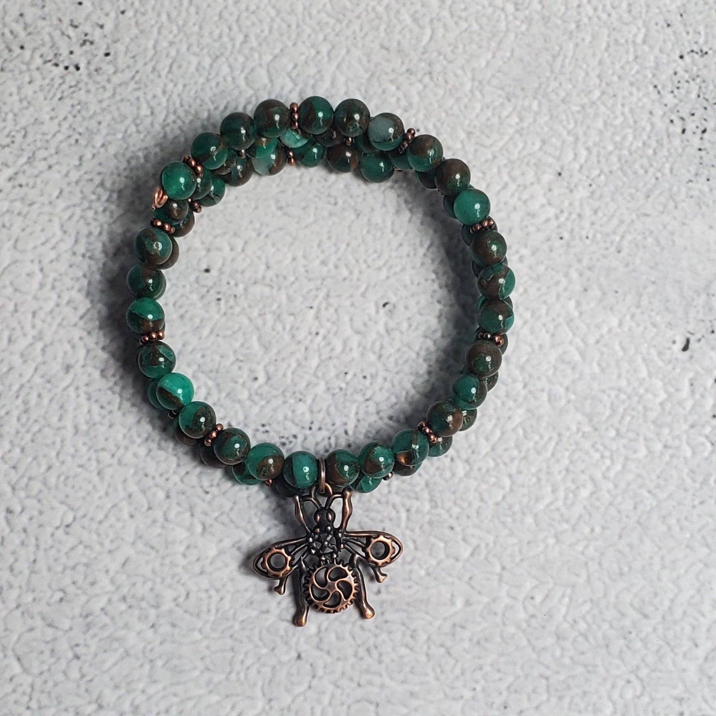 Handcrafted steampunk industrial bracelet with copper beetle charm and green resin sponge quartz on memory wire cuff