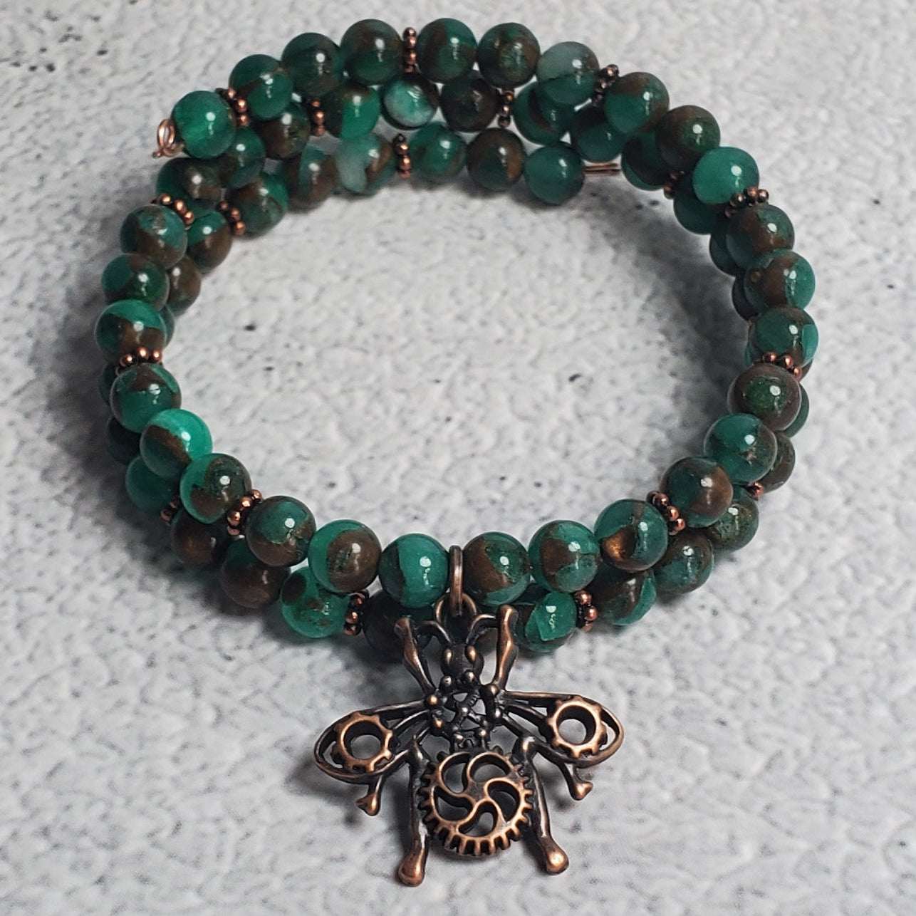 Handcrafted industrial bracelet with copper beetle charm and green resin sponge quartz on memory wire cuff