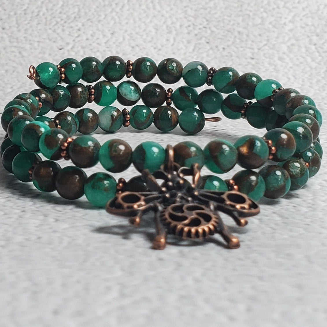 Handcrafted industrial bracelet with copper beetle charm and green resin sponge quartz on adjustable memory wire cuff