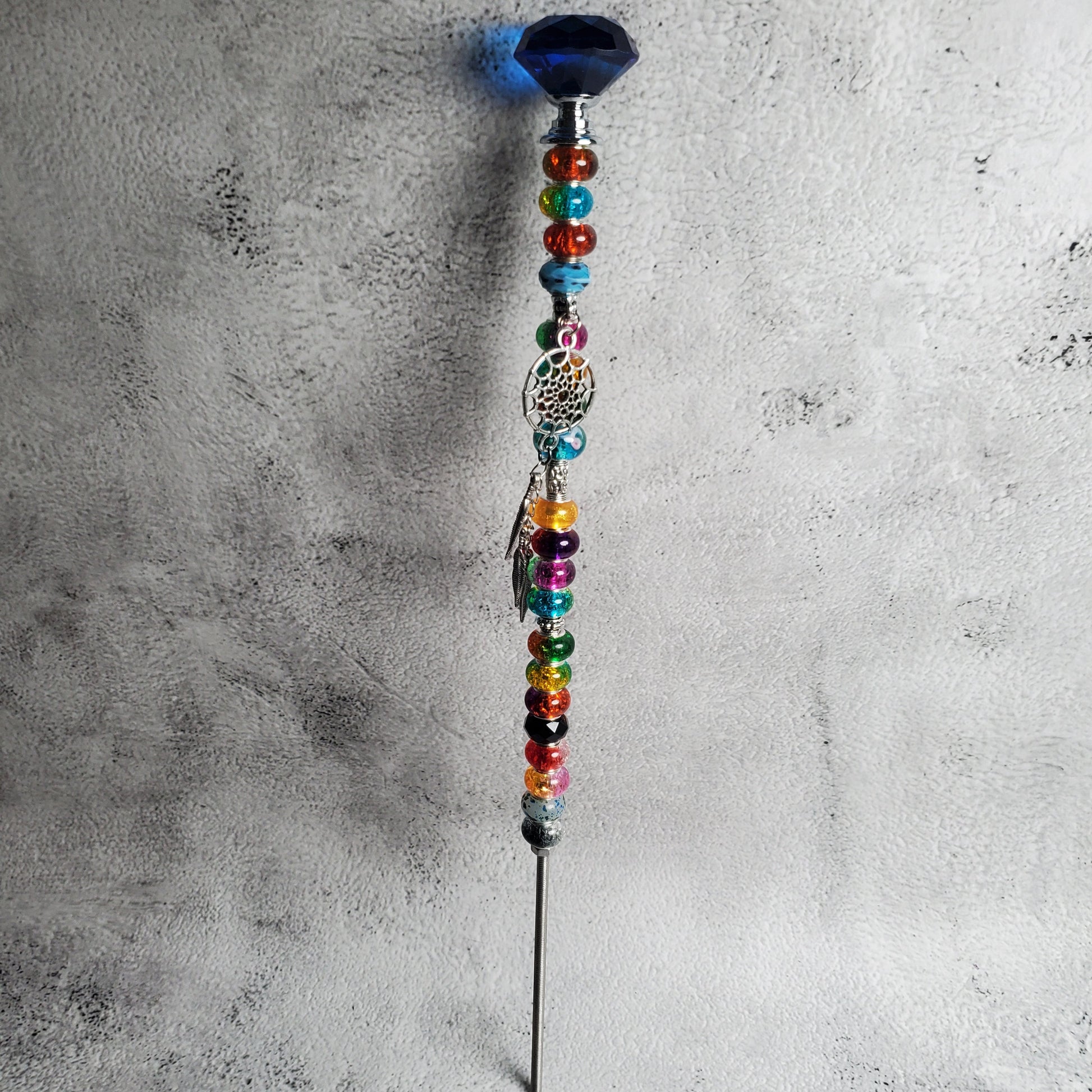 Decorative wand with colorful beads on a textured gray surface