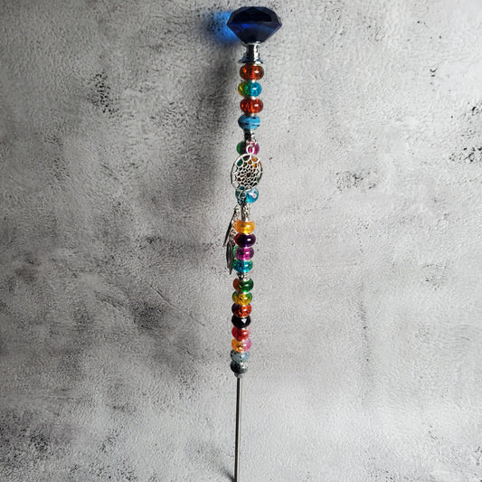 Decorative wand with colorful beads on a textured gray surface