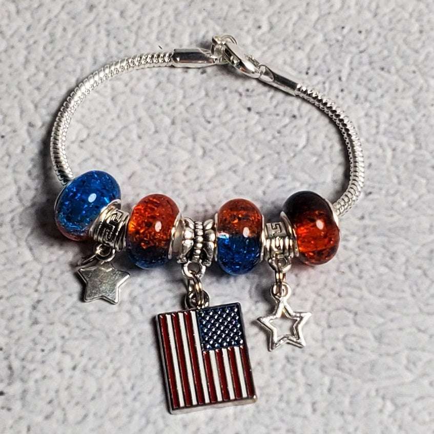 Child's 4th of July patriotic charm bracelet with red and blue beads, pewter stars, and American flag centerpiece on snake chain
