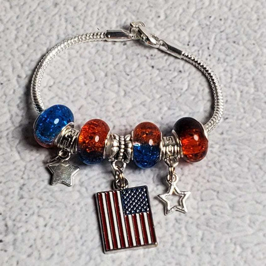 Child's 4th of July patriotic charm bracelet with red and blue beads, pewter stars, and American flag centerpiece on snake chain