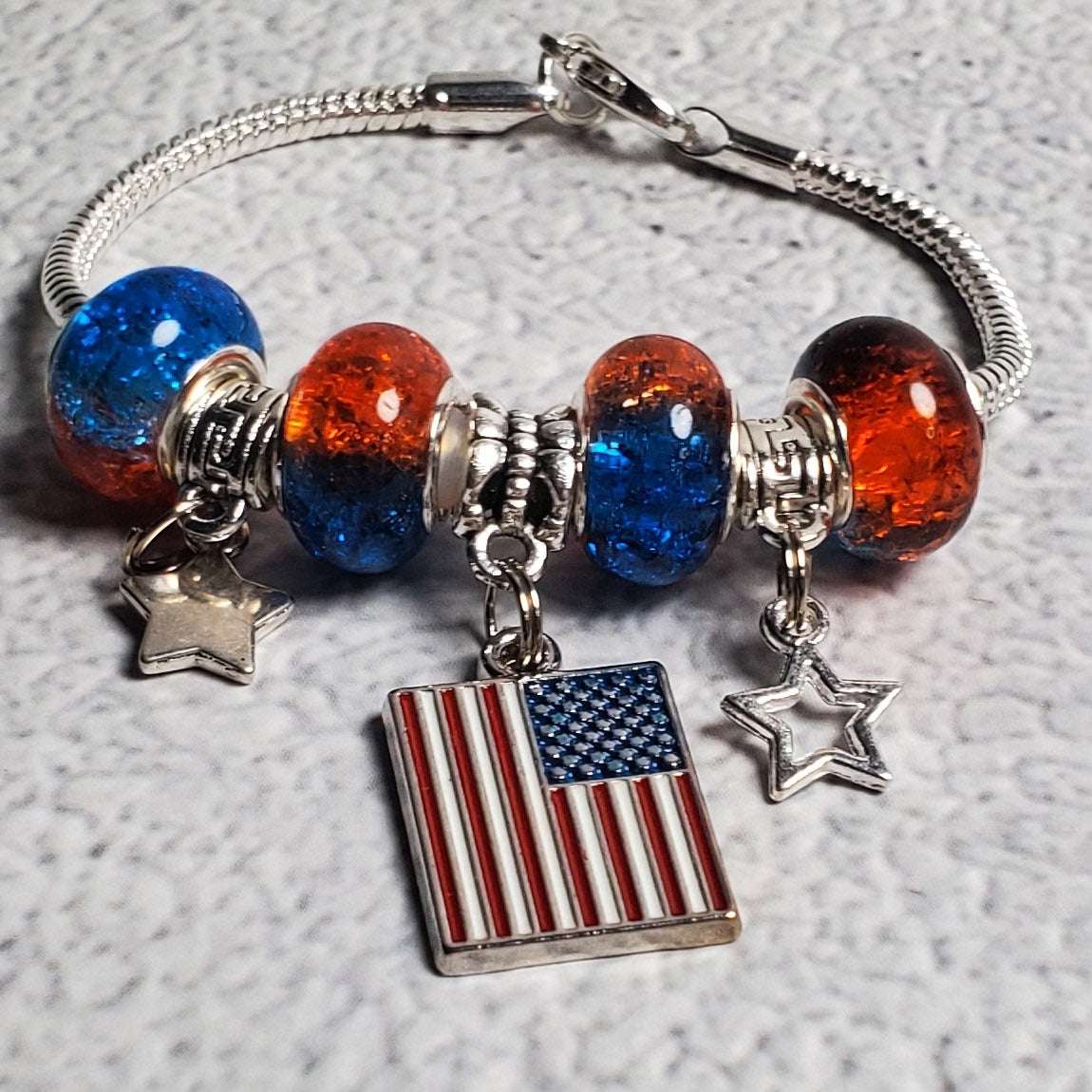 Child's 4th of July charm bracelet with red and blue beads, pewter stars, and American flag centerpiece on snake chain