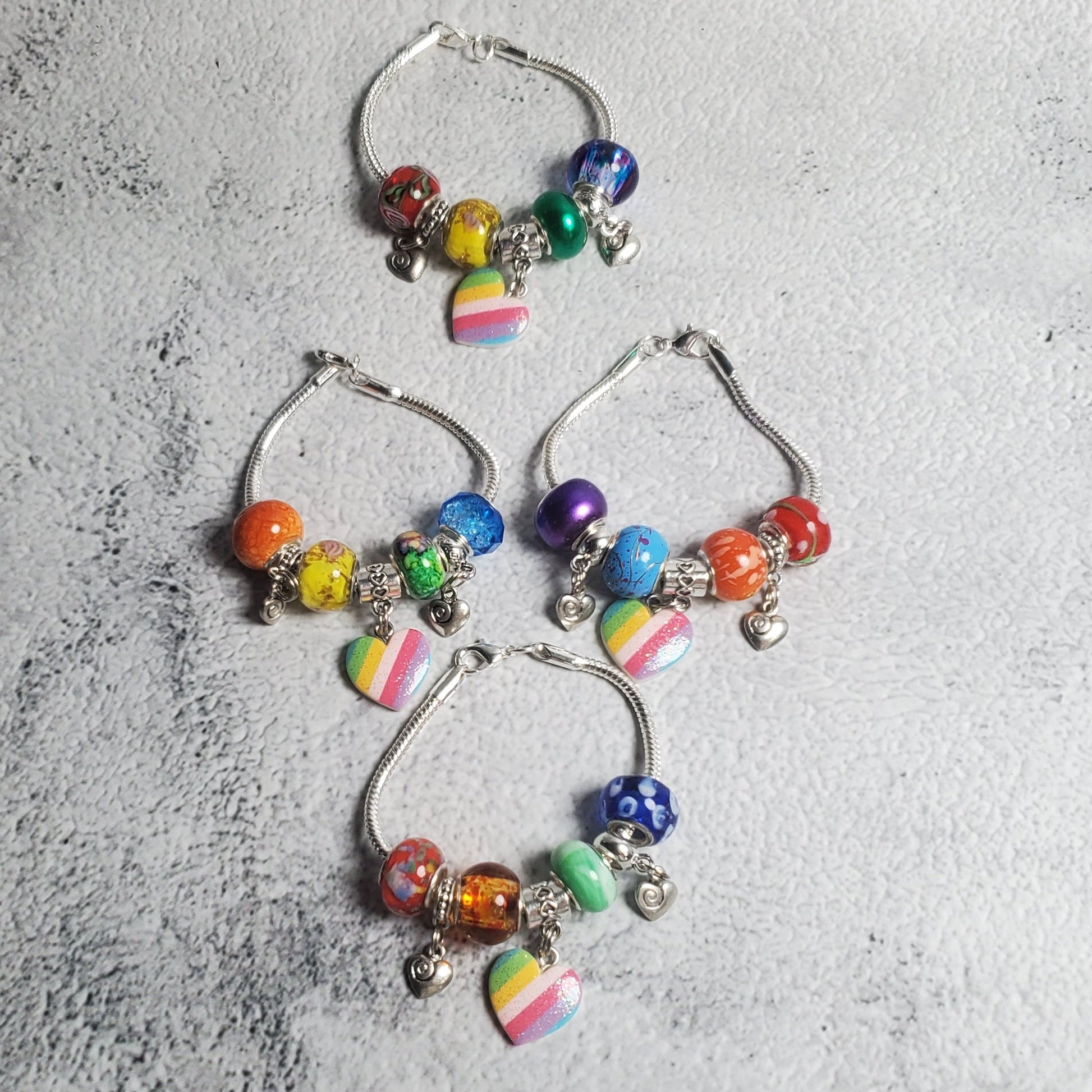 Colorful charm bracelet for children with rainbow beads and heart accents on a smooth snake-chain base