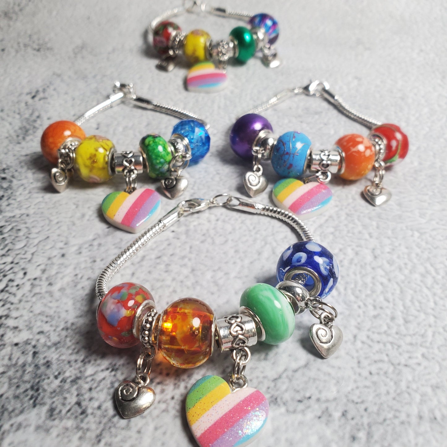 Colorful children's charm bracelet with rainbow beads and heart charms on a silver snake chain
