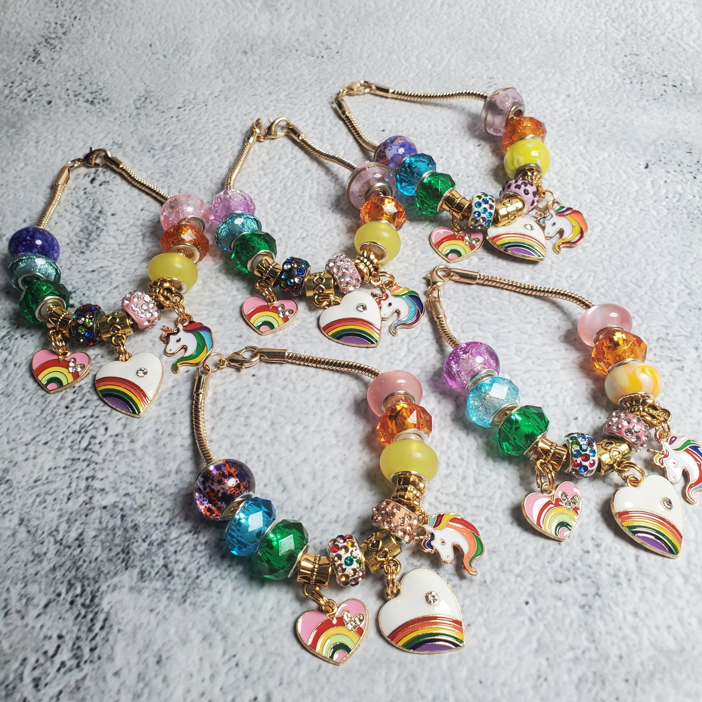 Colorful Charm Bracelet with rainbow beads and brass unicorn and heart charms on flexible snake chain