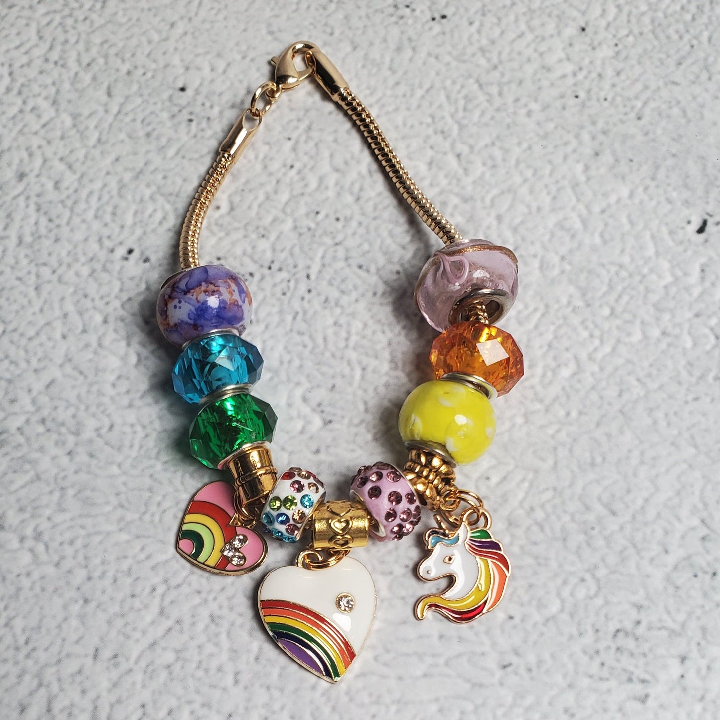 Colorful Charm Bracelet with rainbow beads and brass unicorn charms celebrating individuality and pride