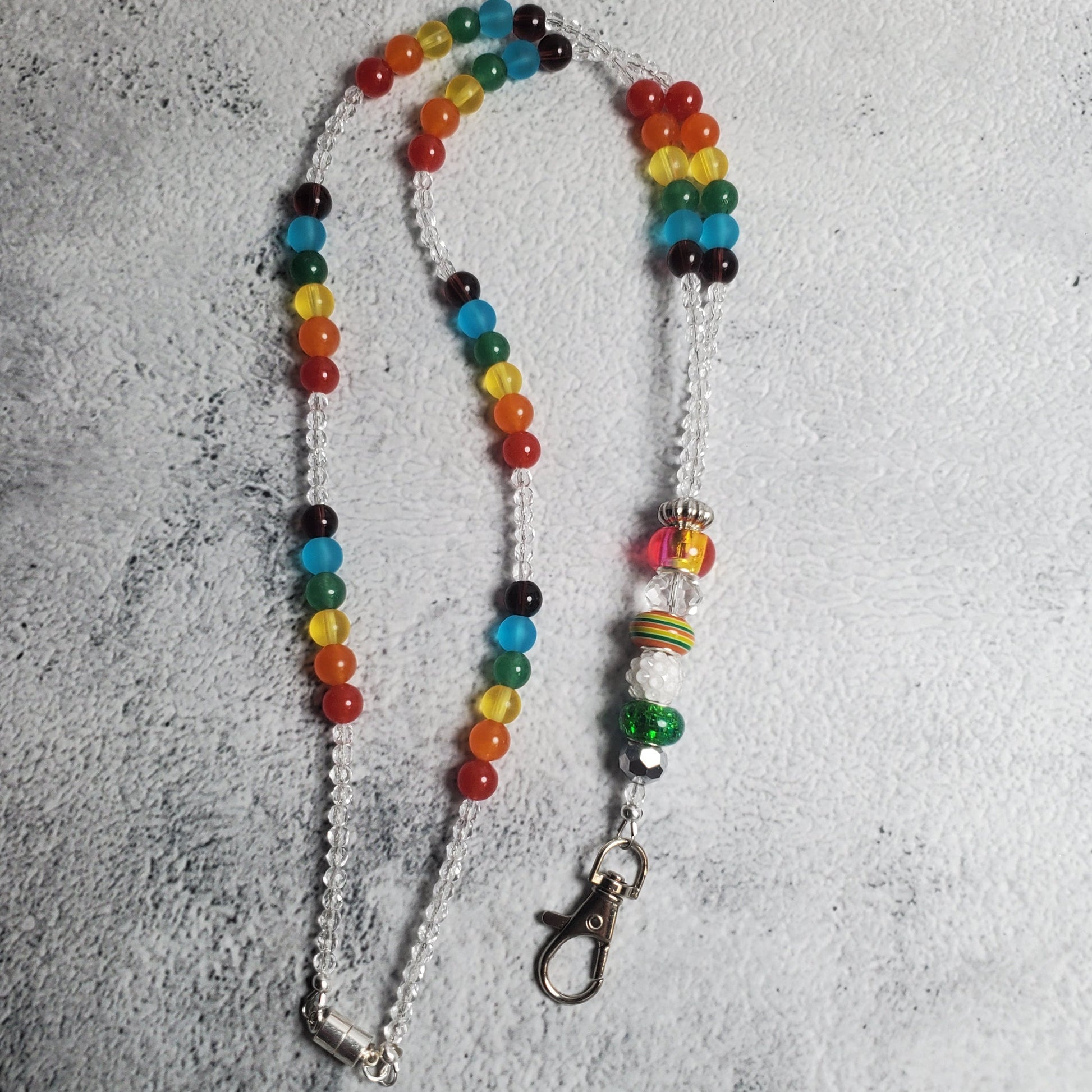 Vibrant rainbow lanyard with colorful glass beads and decorative charm beads, featuring a secure lobster claw clasp and magnetic closure for keys and badges.
